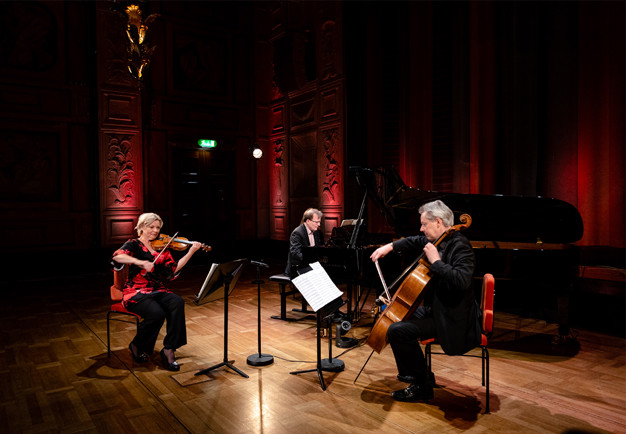 En pianist, en cellist och en violinist. Fotografi.