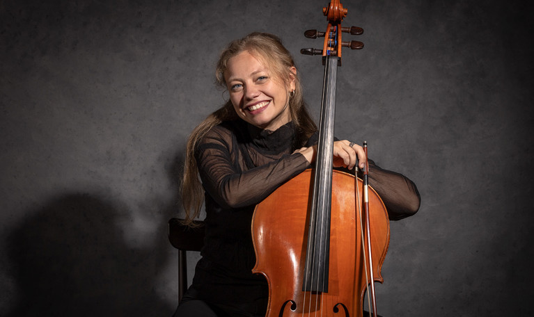 Porträttbild på en leende kvinna med cello. Fotografi.