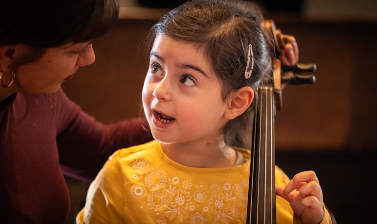 Liten tjej som spelar cello. Fotografi.