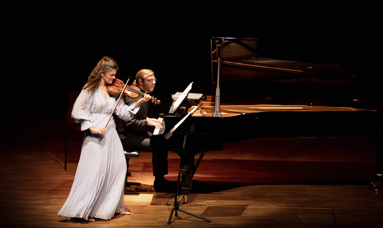 Kvinna som spelar violin och man som spelar piano. Fotografi.