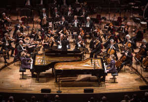 Två killar som spelar piano. Fotografi.