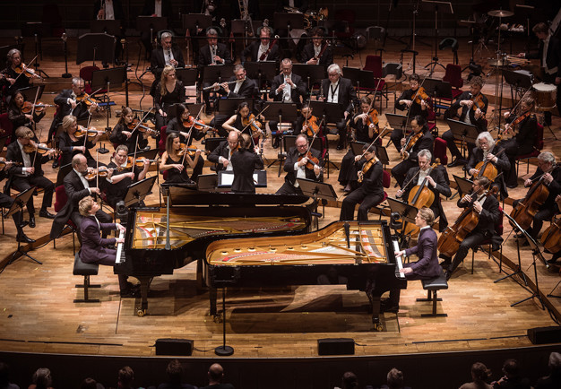 Två killar som spelar piano. Fotografi.