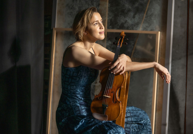 Kvinna som sitter med en violin. Fotografi.