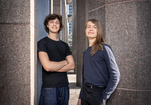Two musicians leaning against a wall. Photo.